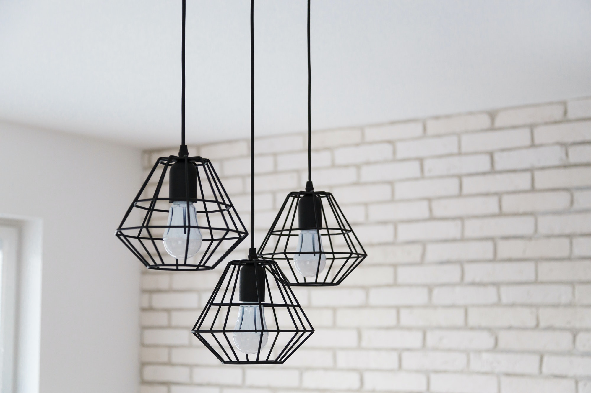 A modern loft chandelier made of black wire in a stylish white interior